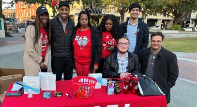 group of students gathered at information table for world aids day