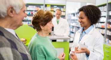 Female pharmacist speaking with patients in pharmacy