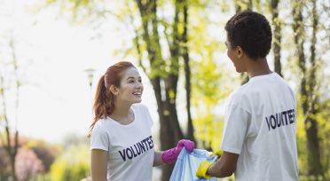 2 volunteers cleaning up trash in park