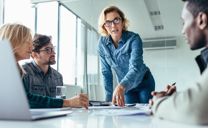 Female leader speaking in boardroom to staff