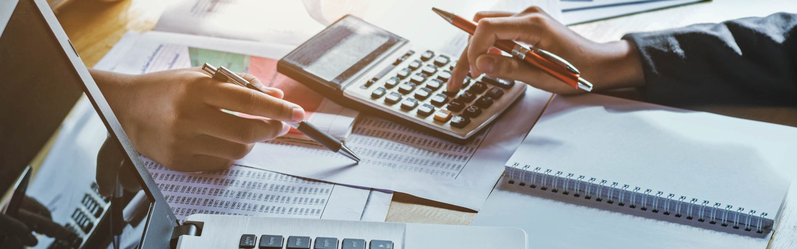 Accountants adding up figures with a calculator on desk