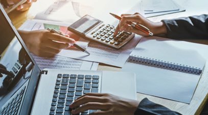 Accountants adding up figures with a calculator on desk