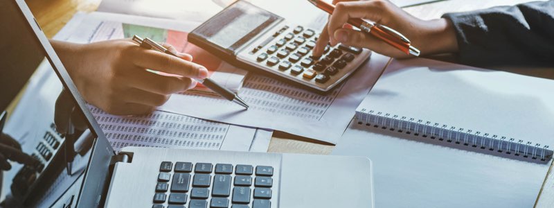 Accountants adding up figures with a calculator on desk