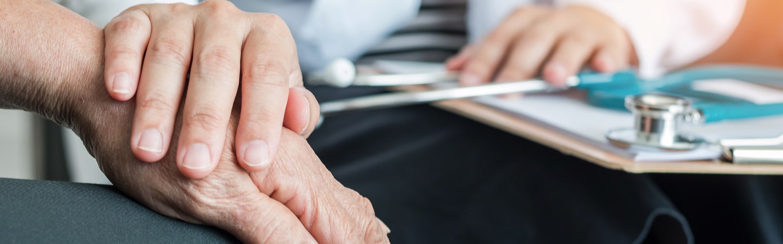 Nurse with hand on older patient's hand