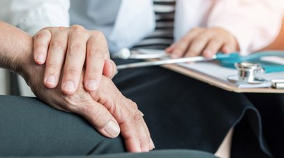 Nurse with hand on older patient's hand