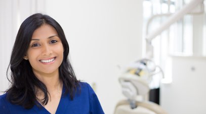 Female nurse smiling in front of medical equipment