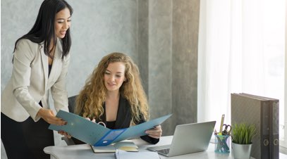 2 Female business professionals reviewing information in folder at desk
