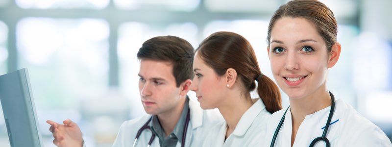 Female healthcare administrator in front of doctor and nurse smiling