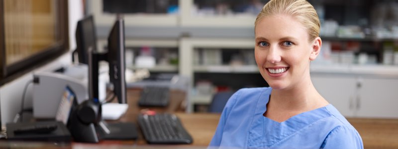 Femaie healthcare administrator sitting at desk smiling