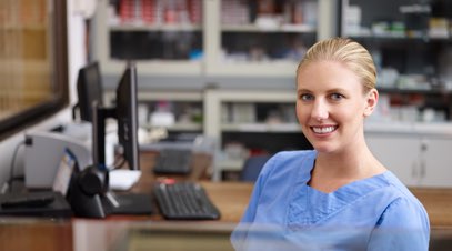 Femaie healthcare practicioner sitting at desk smiling