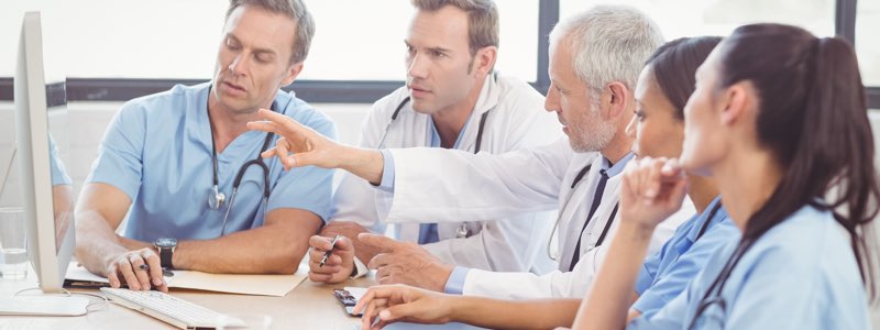 Team of nurses and doctor discussing information on a computer