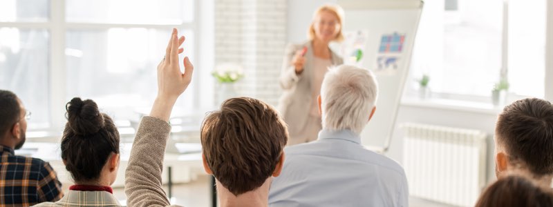 Woman teaching a class with hand raised