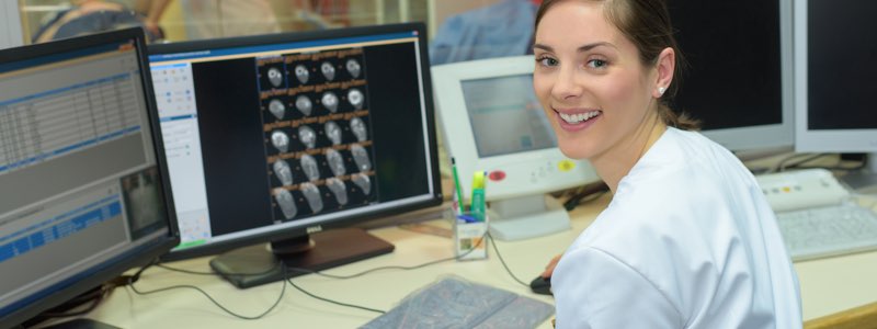Female nurse in front of computer screen smiling