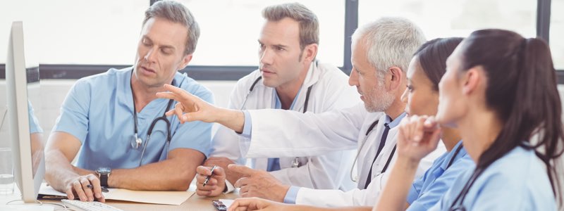 Team of nurses and doctor discussing information on a computer