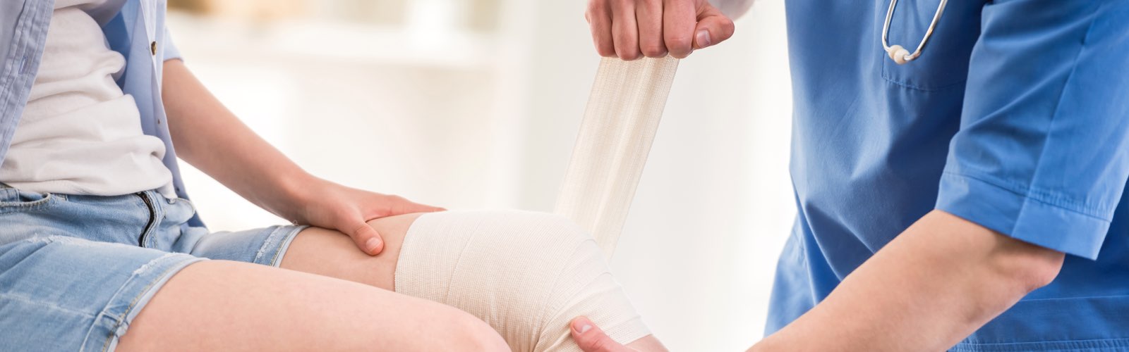 Nuse wrapping patient's knee with a bandage