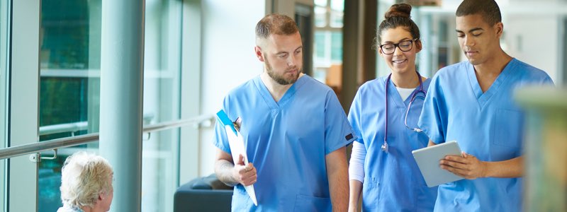 3 nurses walking through hospital talking