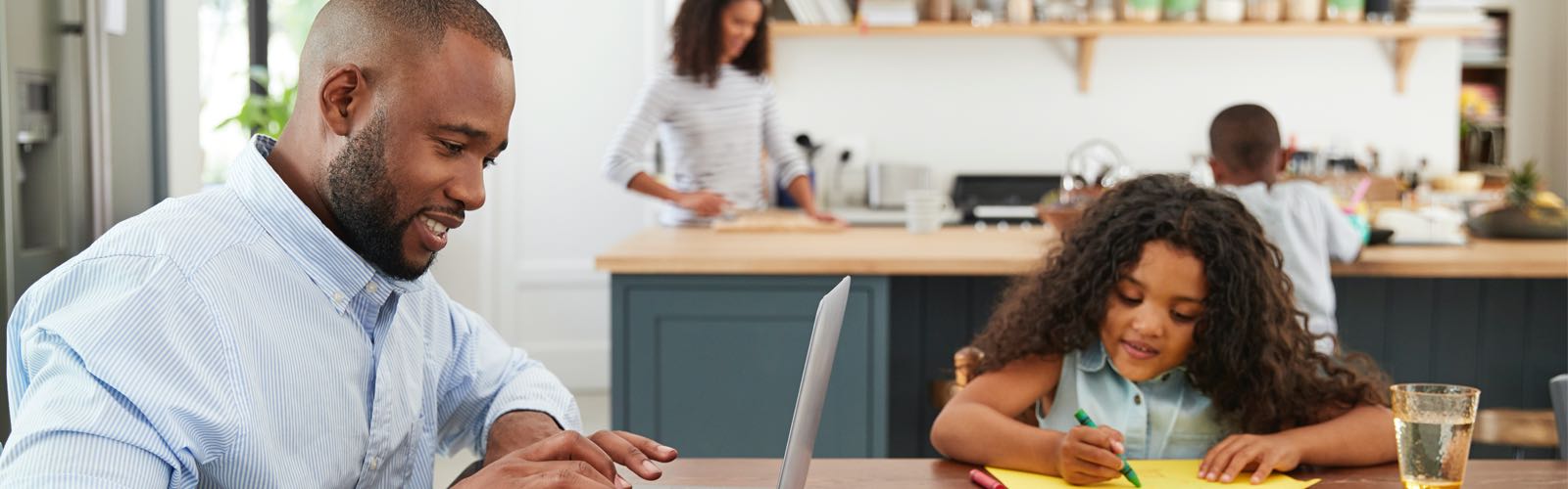 Male student at home with family learning on laptop