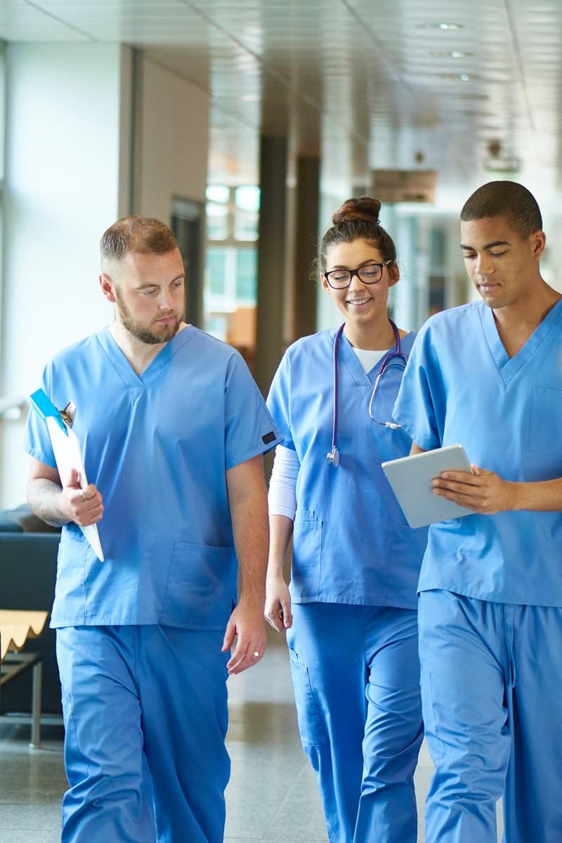 3 nurses walking through hospital talking