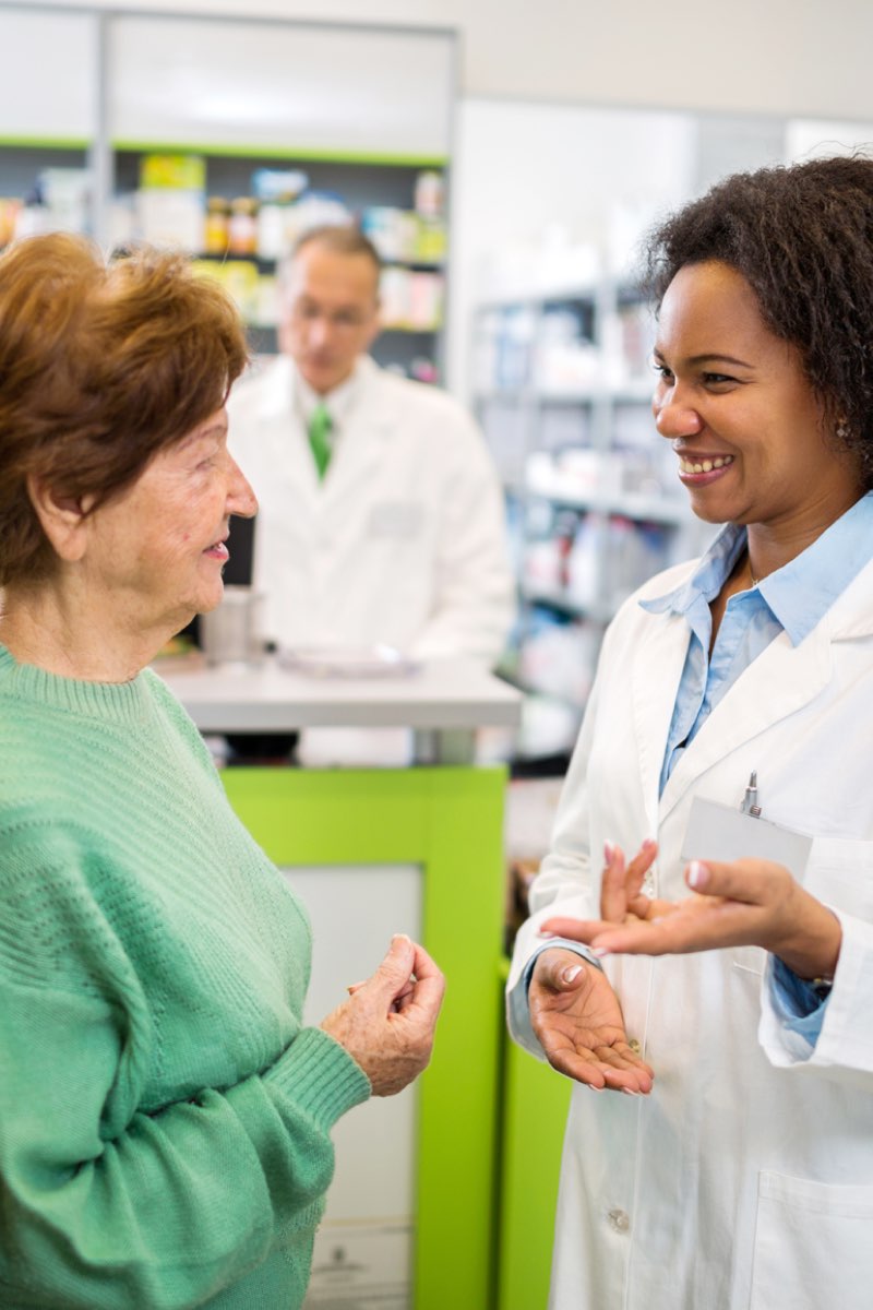 Female pharmacist speaking with patients in pharmacy