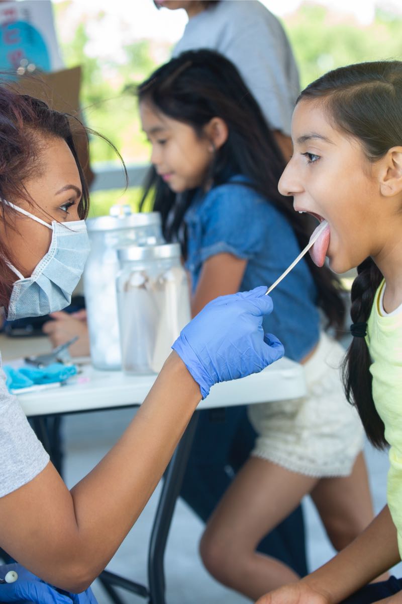 Healthcare worker swabbing child's tongue