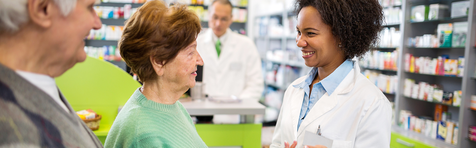 Woman pharmacist in pharmacy consulting elderly patients