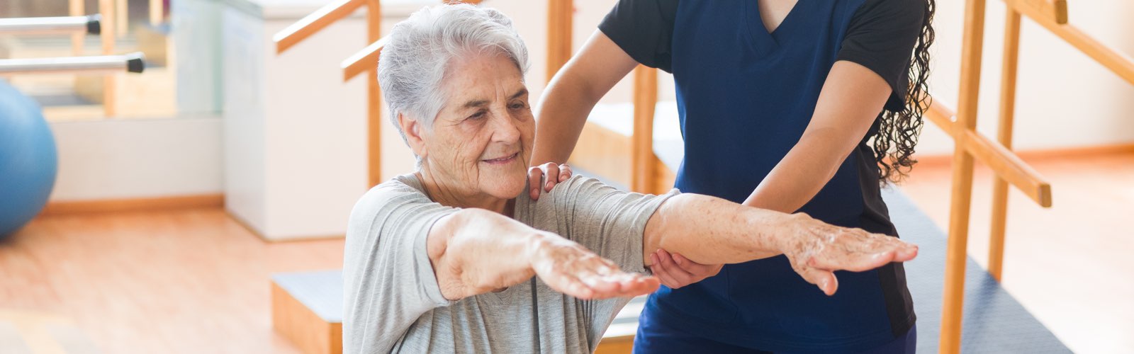 Physical therapist holding older patient's arms outstretched