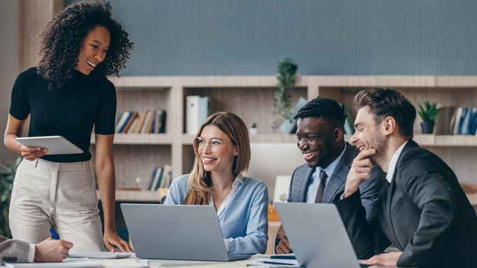 Female leader smiling with colleagues on laptops