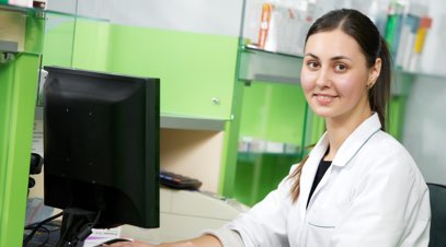 Female nurse in front of computer smiling