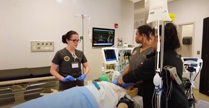 three healthcare workers studying the administration of anesthesia in a hospital room setting