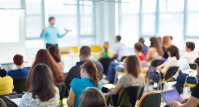 variety of adults sitting in a class room listening to an instructor give a presentation