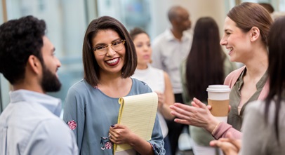 four young professionals talking toeach other in a hallway