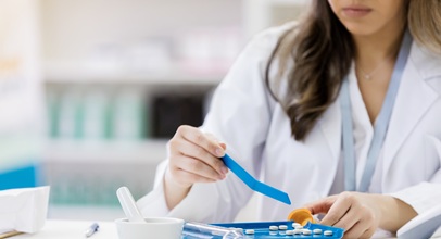 woman in white medical coat measuring medications in a pharamacy