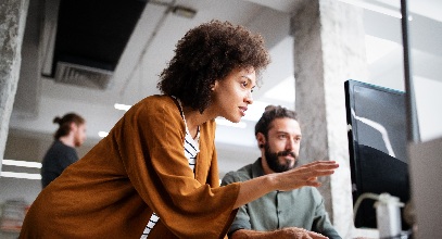 a woman and a man having a discussion as they look at a computer screen together