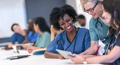 several nursing students in scrubs in a classroom working together