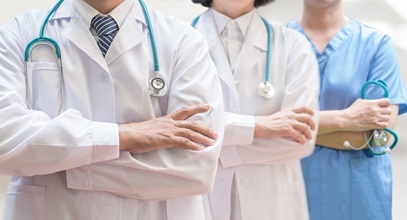 three hospital professionals, one man and two women, standing in a hallway holding their stethescopes