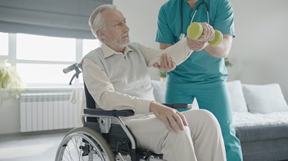 older gentleman sitting in a wheelchair receiving help with weight lifting from physical therapy assistant