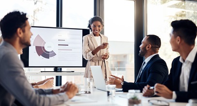 one woman person of color presenting a graph to several male colleagues