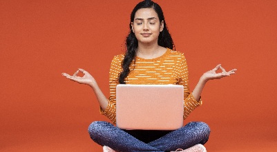 young woman with long dark hair sitting cross legged with a laptop on her legs meditating