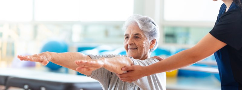 Physical therapist holding older patient's arms outstretched