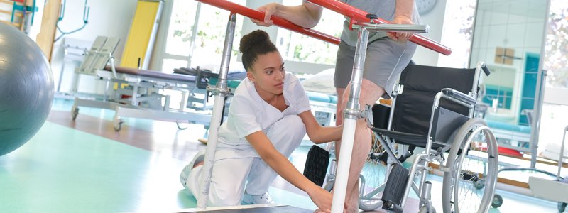 Physical therapist helping patient walk with support