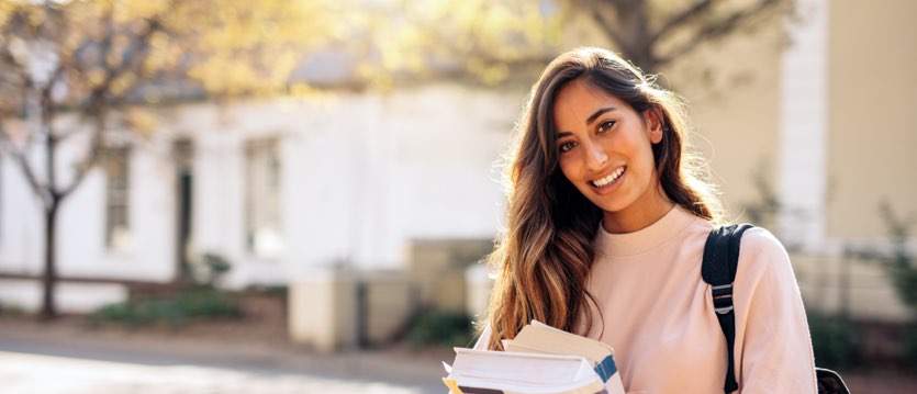 female student smiling walking into campus