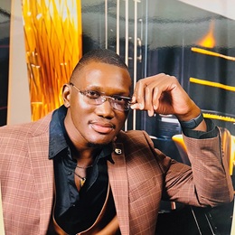 Brandon Vixamar headshot in a dark button down shirt and salmon blazer