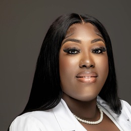 Charlene Coates headshot wearing a white jacket and white pearls