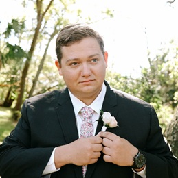 Zachary Hall in wedding suit outdoors with trees behind him