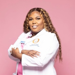 LaTorya Amour headshot in a long white medical coat and pink scrubs