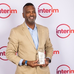 Waddie Freeman headshot wearing a tan suit carrying a glass award