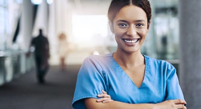 female standing in a hospital hallway wearing scrubs